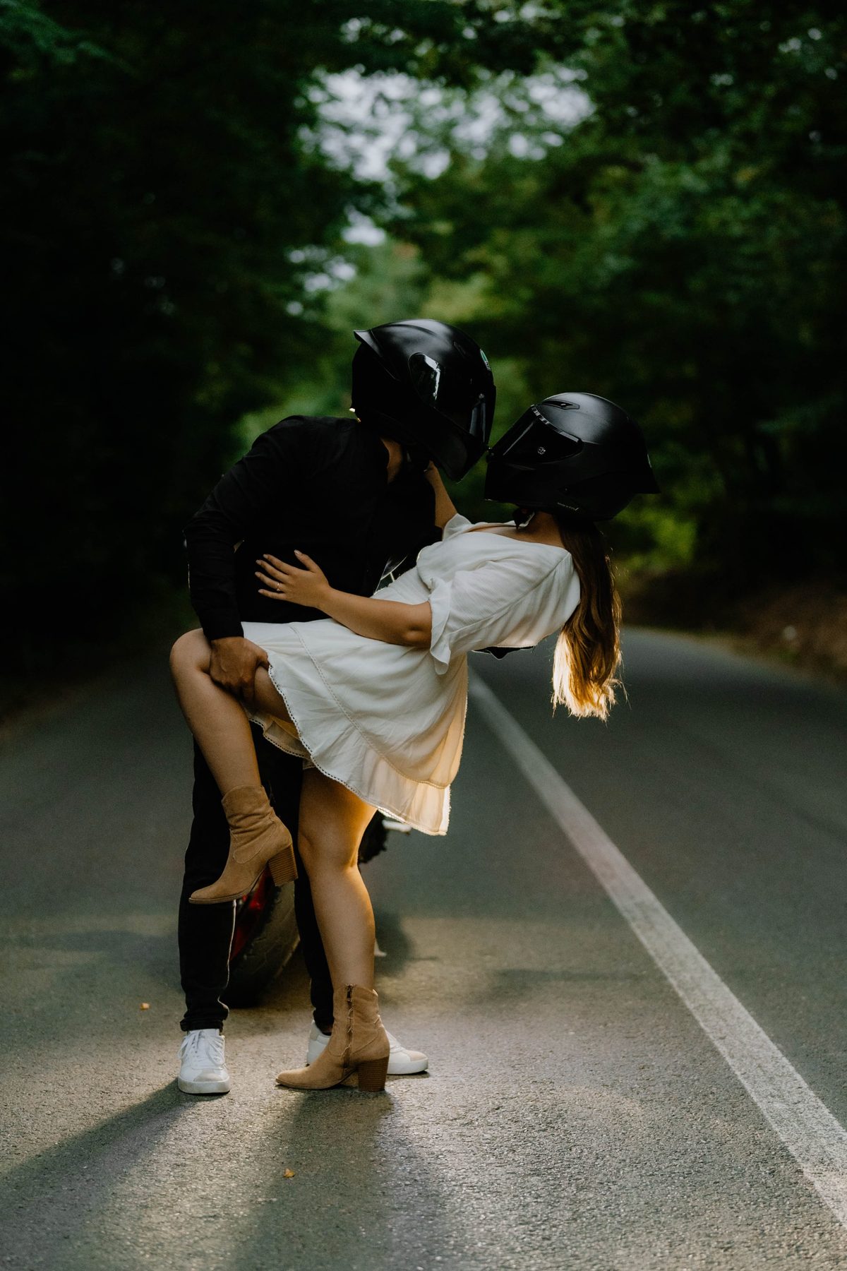 Cuplu cu căști de motociclist, sărut pe șosea