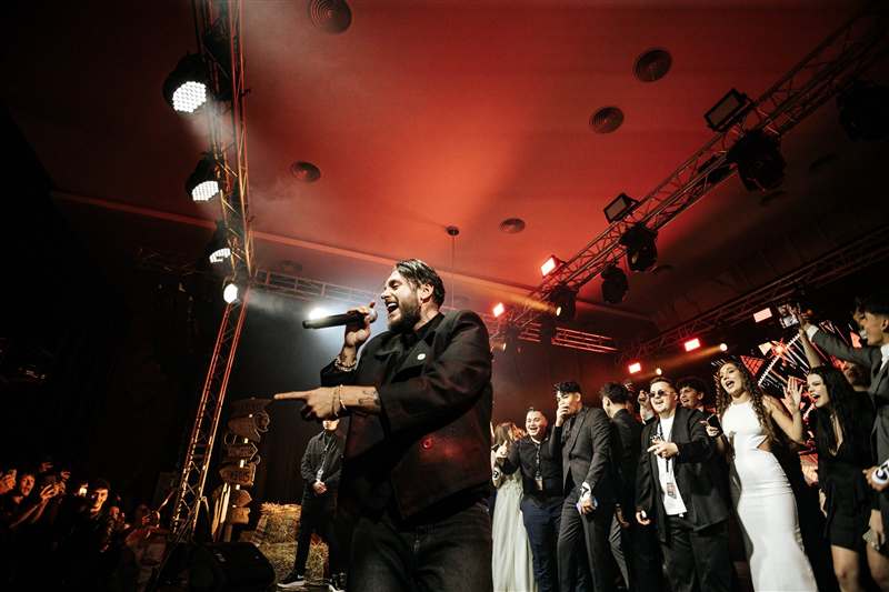 Solist cântând cu publicul în spate, lumini verzi și galbene